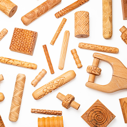 assortment of wooden textured rollers and stamps with a variety of designs careved into them